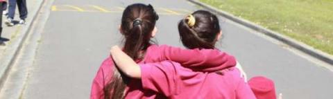 This images shows girls walking away from the camera with arms around each others shoulders