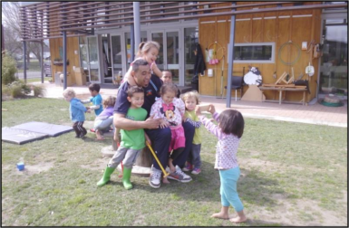 A man plays outside with several young children.